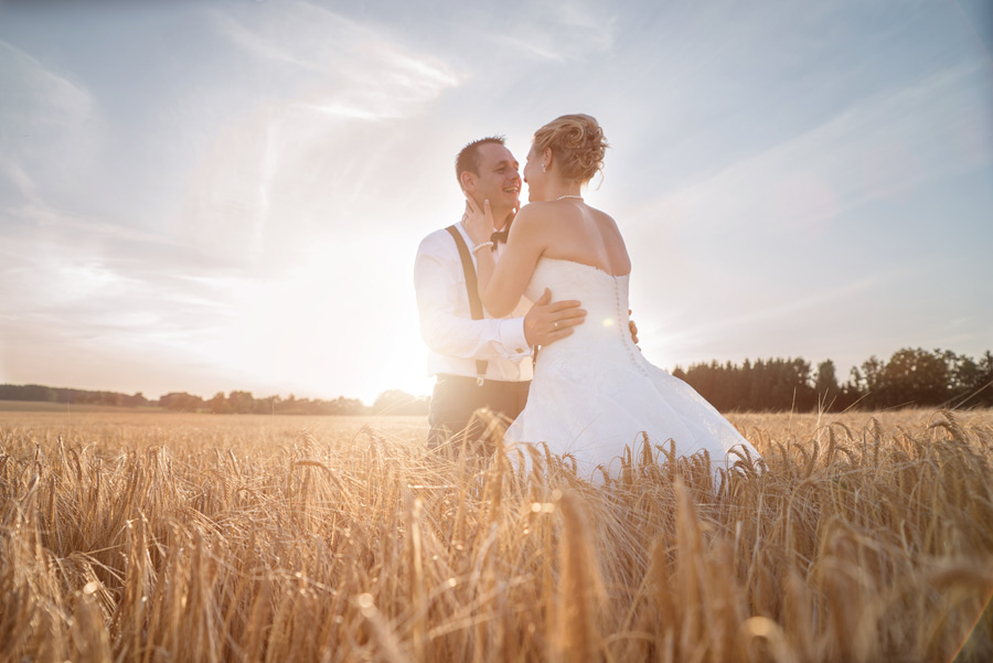 Hochzeitspaar bei untergehender Sonne im Kornfeld