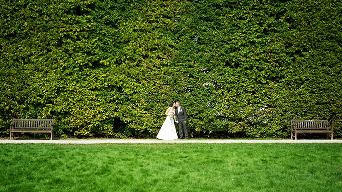 Hochzeitspaar vor großer Hecke